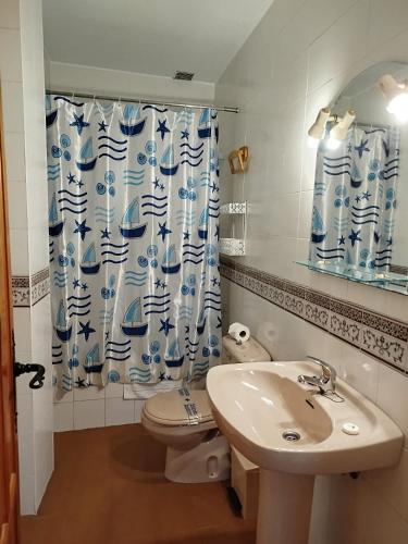 a bathroom with a sink and a toilet and a shower curtain at Apartamentos Turísticos Rural Los Tinaos in Bubión