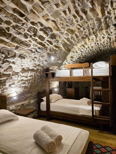 a bedroom with two bunk beds and a stone wall at Jeanette's Home in Berat