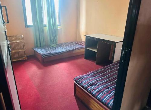 a room with two beds and a desk in it at Amazon Boys Hostel in Kathmandu