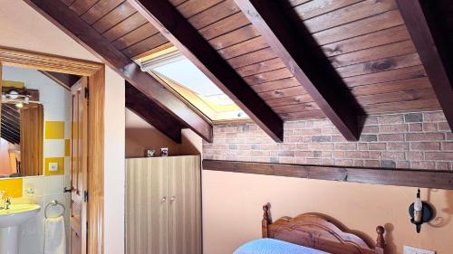 a bedroom with a bed and a ceiling with wooden beams at Casa Cuevas in Caín