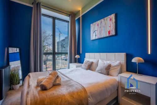 a bedroom with blue walls and a large bed at Spacious Manchester City Condo - Parking - Next To AO Arena - Local Attraction & Transport Links in Manchester