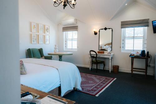 a bedroom with a bed and a table and a mirror at Le Petit Paris in Franschhoek