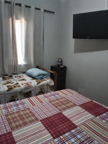 a bedroom with two beds and a flat screen tv at Hostel caminho da Serra in São Pedro
