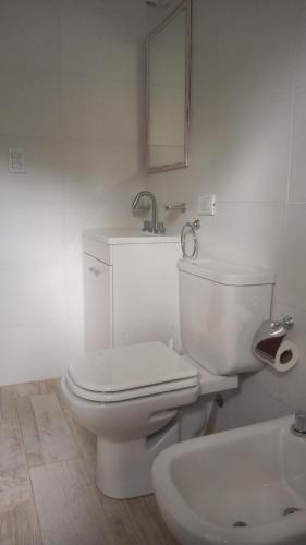 a white bathroom with a toilet and a sink at Bosque y Mar in Mar Azul