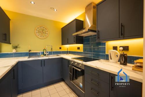 a kitchen with blue cabinets and a clock on the wall at Central Manchester City Apartment - Next To AO Arena - With Parking in Manchester