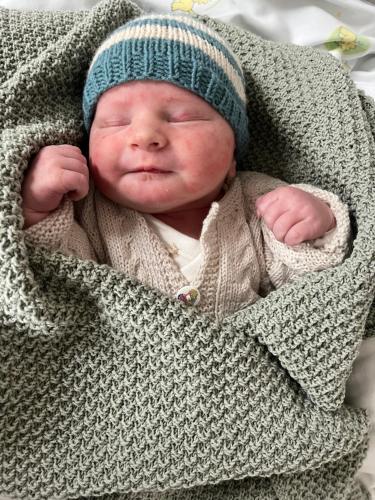 a newborn baby wearing a sweater and a hat at Ravn in Vistad