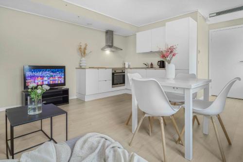 a kitchen and living room with a white table and chairs at Contemporary city-apartement with views of the dock! in Bergen