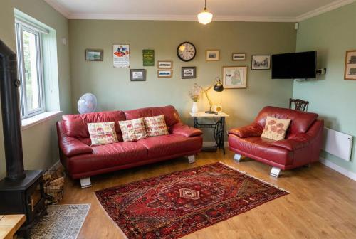 a living room with a red couch and a chair at Stylish Morpeth Cottage with Log Burner, Garden and Free Parking in Morpeth