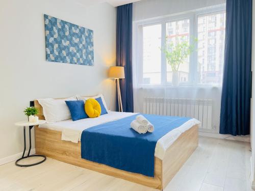 a bedroom with a bed with blue and yellow pillows at 417I2 Gray and Yellow apartment Sholpan city in Almaty