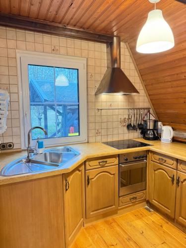 a kitchen with wooden cabinets and a sink and a window at Ferienhaus am Mescheriner See in Mescherin