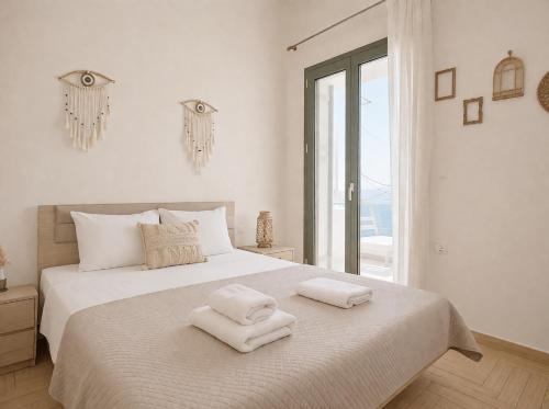 a bedroom with a white bed with two towels on it at Elysian Seaside Villa in Almyrida