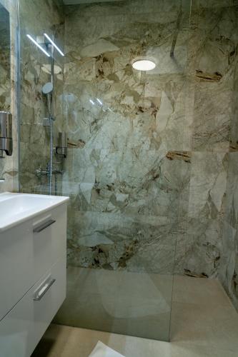 a bathroom with a glass shower and a sink at SEE YOU Apartments in Niš