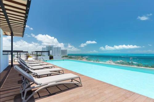 a swimming pool with lounge chairs and the ocean at Beautiful sea view apartment in the Hotel Zone Cancun in Cancún