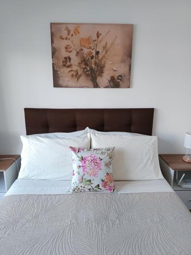 a bed with two pillows and a painting above it at Cómodo apartamento céntrico con garaje in Montevideo