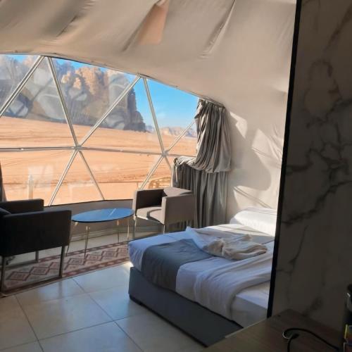 a bedroom with a bed and a large window at Bedouin Life Camp in Aqaba
