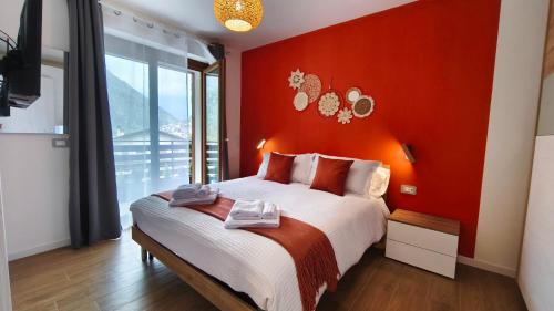 a bedroom with a red wall with a bed at San Martì Casa Vacanze in Piazza Brembana