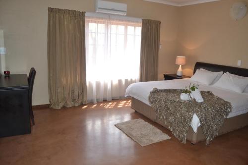 a bedroom with a bed and a large window at Thabaledi Game Lodge in Brits