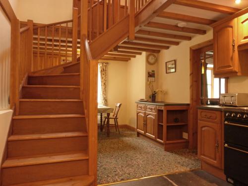 a kitchen with a spiral staircase in a house at Granar Gynolwyn in Abergynolwyn