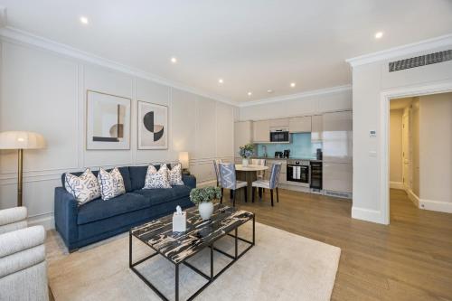a living room with a blue couch and a table at Buckingham & Lloyds Knightsbridge in London