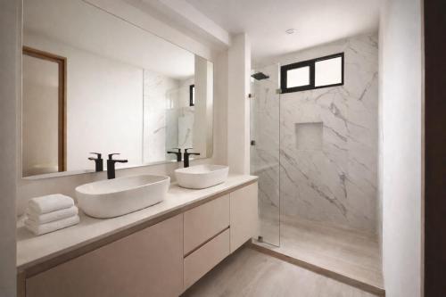 a white bathroom with two sinks and a shower at Garden Atelier - Private Cenote & Steps from the Beach in Tulum