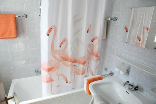 baño con cortina de ducha con flamencos. en Pension Maria en Antdorf