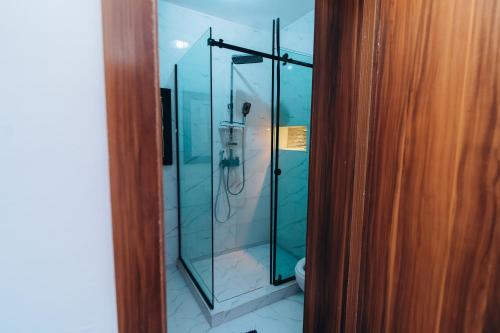 a glass shower in a bathroom next to a wooden door at VHS Vinchee Suites II in Lagos