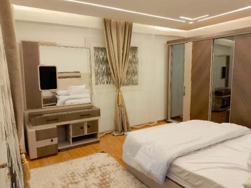 a white bedroom with a bed and a television at النور للاستثمار العقاري بالمنيل in Cairo