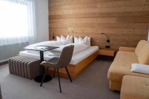 a bedroom with a bed with a table and a chair at Berghaus Schäfer in Faschina