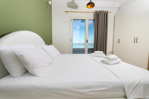 a white bed with a view of the ocean at Perla Luxury Apartment - Private Patio & Parking in Vlorë