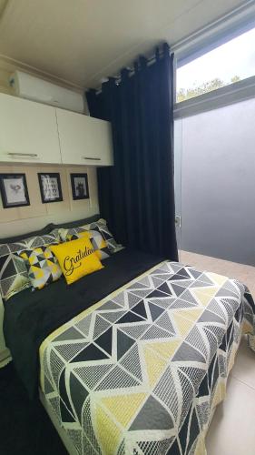 a bedroom with a bed with a black and yellow comforter at Blessed Homes in Braço do Norte