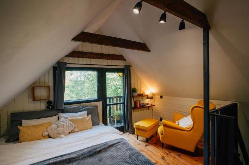 a bedroom with a bed and a yellow chair at Naše chata in Ostrolovský Újezd