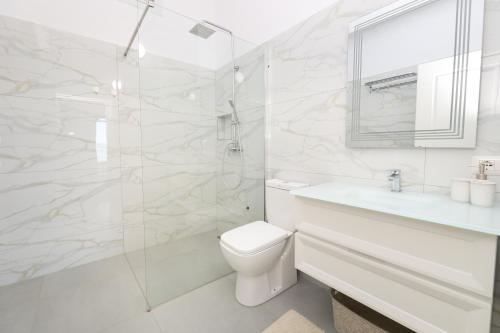 a white bathroom with a toilet and a sink at Perla Luxury Apartment - Private Patio & Parking in Vlorë