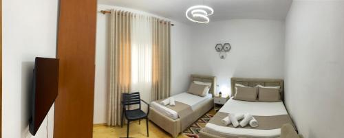 a bedroom with a bed and a couch and a tv at Guest House Brahimasi in Çorovodë