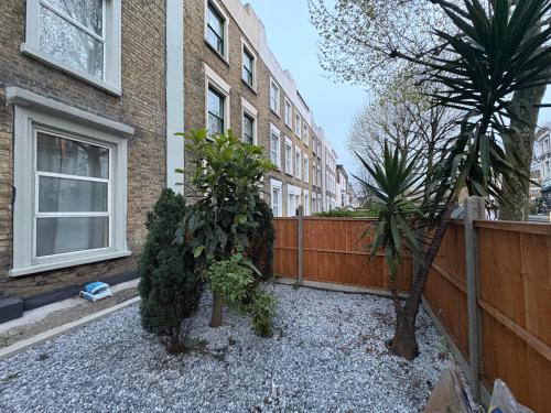 a house with two trees in front of a fence at Comfort at Sunderlands in Forest Hill