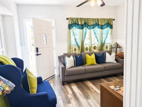 a living room with a couch and blue and yellow pillows at 3BR St Pete Home Sleeps 6 Private Backyard 15 Min to Beach in St. Petersburg