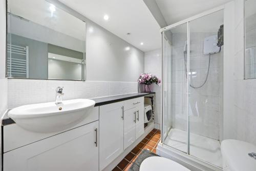 a white bathroom with a sink and a shower at Lee Valley Lodge Upper Floor in Cheshunt