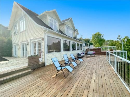 a deck with chairs and a house at La Maison Jaune in La Malbaie