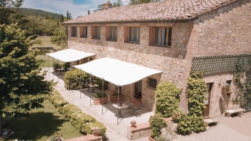 an external view of a building with white awnings at Holistic Hotel MadreSelva in Casole dʼElsa