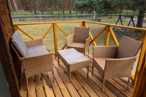 three chairs and a table on a porch with a playground at Лісова Хатка in Parowa