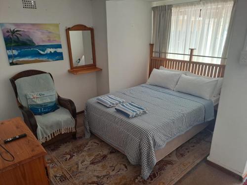 a bedroom with a bed and a chair and a mirror at 65 Rowweklip in Jongensfontein