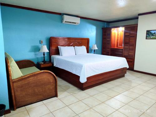 a bedroom with a large bed and a chair at Fish Hook Marina Hotel in Golfito