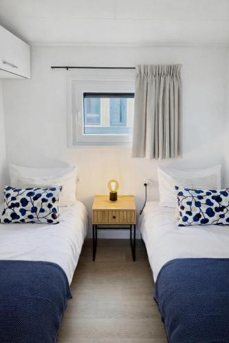 two twin beds in a room with a table at Colibri Huisje in Haarle