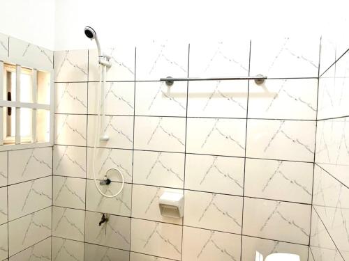 a bathroom with a shower with white tiles at Hebertogo Téléssou in Midja