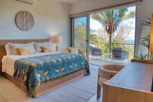 a bedroom with a bed and a balcony with a palm tree at Ocean View Tranquility 2BR with Pool in San Juanillo