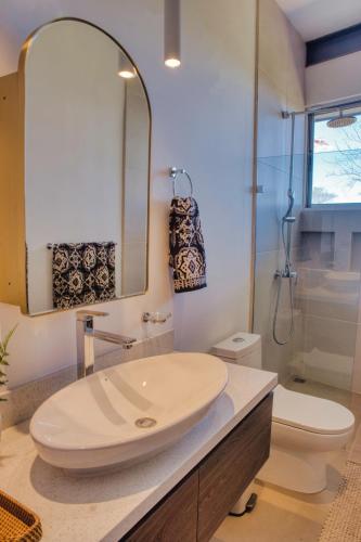 a bathroom with a sink and a toilet and a mirror at Ocean View Tranquility 2BR with Pool in San Juanillo