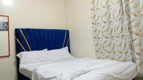 a bed in a room with a blue headboard at Jayson Homes in Thika
