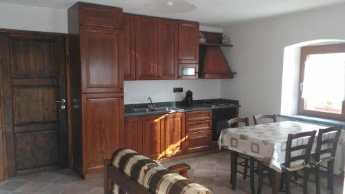 una cocina con armarios de madera, mesa y fregadero en Maison Bellevue VDA-PERLOZ-N 0001 en Pont-Saint-Martin