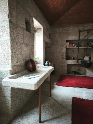 a stone room with a table and a red rug at Casa do Cabo in Ribeira de Pena
