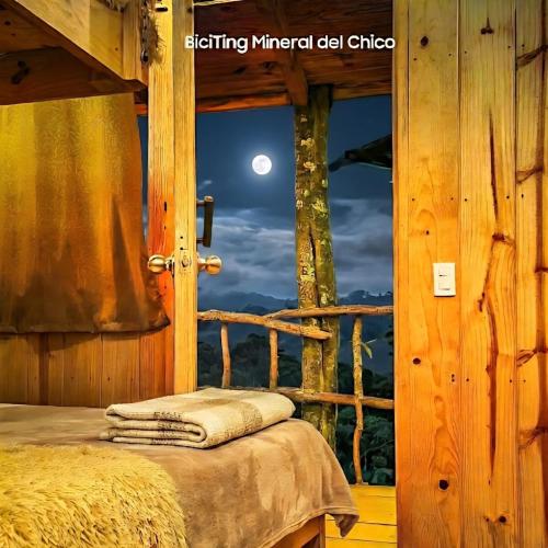 a room with a bed and a window with a full moon at Biciting Casita en el Árbol con Terraza in Mineral del Chico