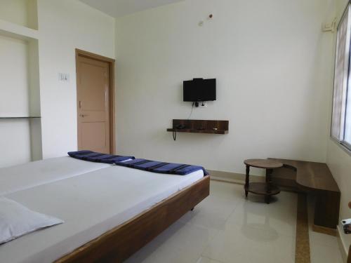 1 dormitorio con 1 cama y TV en la pared en Shri Gita Hotel, en Raipur